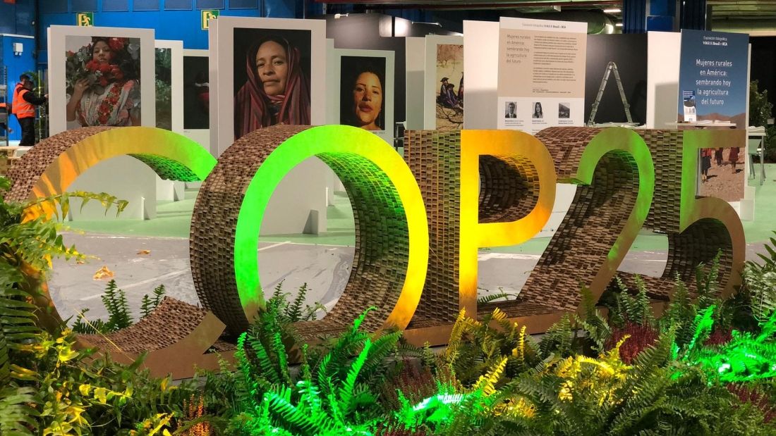 De fondo parte de la muestra fotográfica “Mujeres Rurales en América: sembrando hoy la agricultura del futuro”, que presentó el IICA en la COP25 en Madrid.